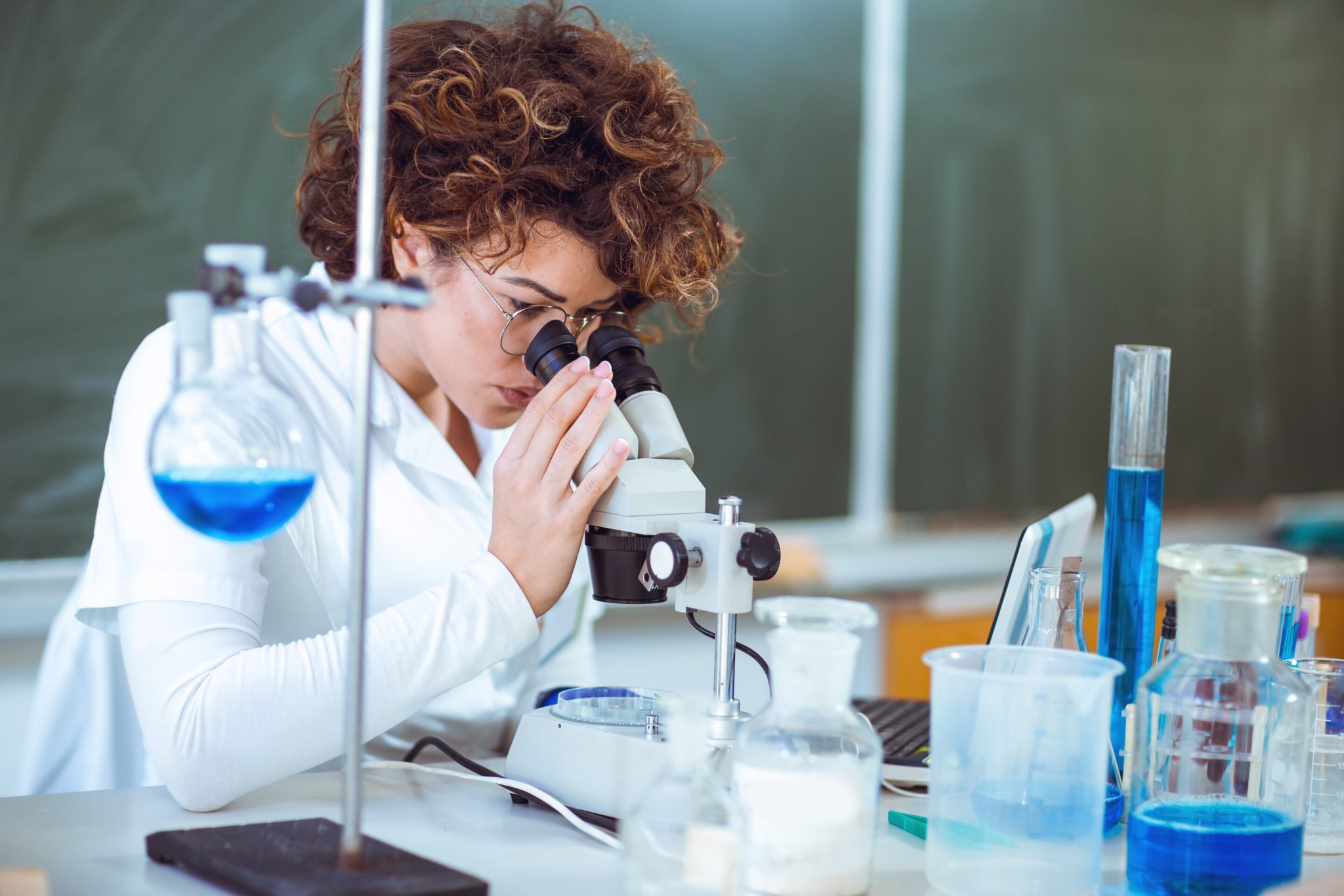 Woman scienist in laboratory. Young scientist looking through a ...